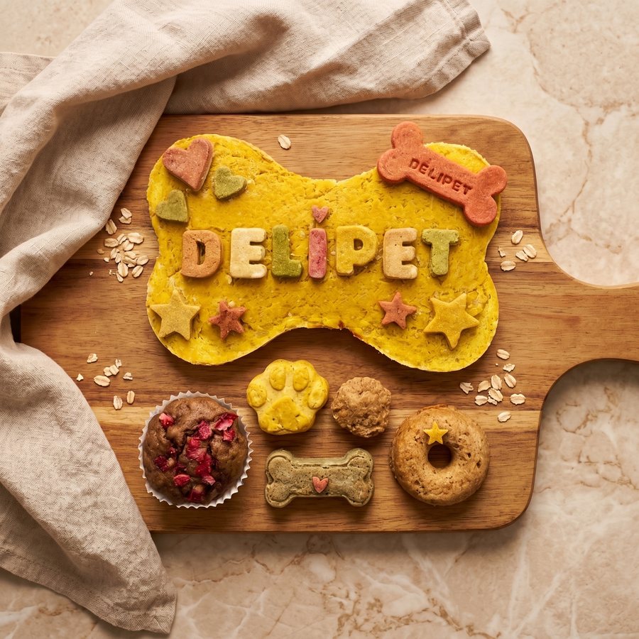 Pack San Roque grande: torta de pollo con forma de hueso y letras DELIPET, estrellas y corazones, y debajo muffin, galleta de huella, snack redondo, hueso y donut